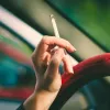 Una mujer sujeta un cigarrillo en el coche