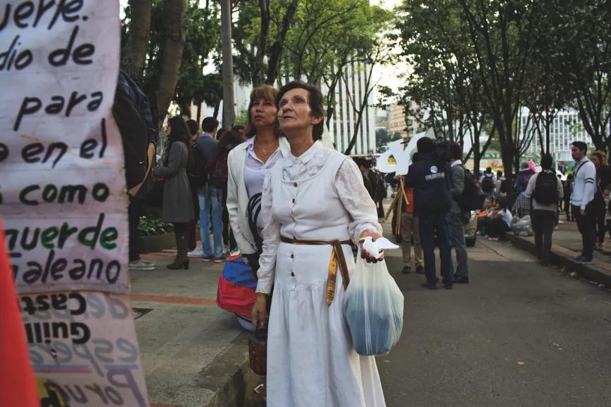 Una mujer de blanco lee un letrero a favor de la resolución del conflicto durante una marcha por la paz en Bogotá el 5 de octubre de 2016
