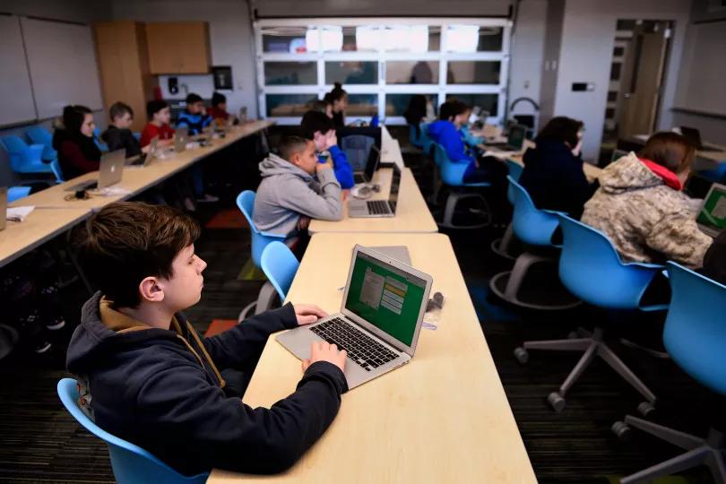 Los estudiantes trabajan con los ordenadores portátiles en el aula de aprendizaje de sexto grado.
