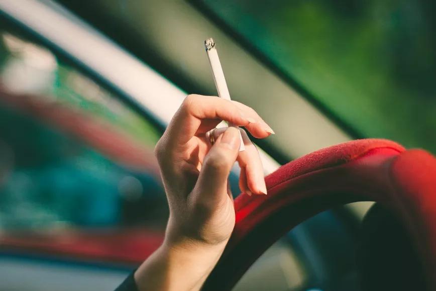 Una mujer sujeta un cigarrillo en el coche