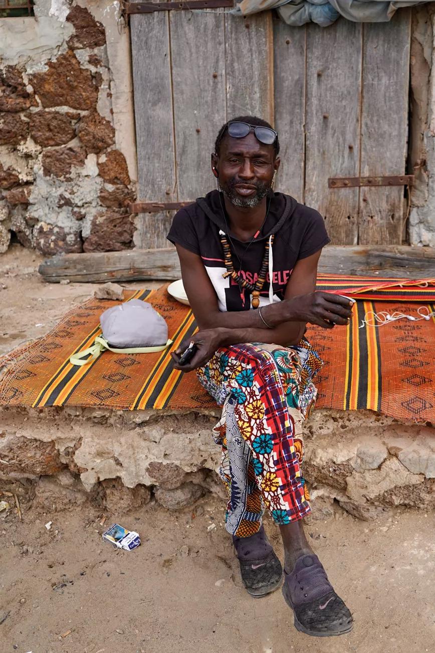 Un viejo Baye Fall ofrece consejos gratis junto a su casa de Dakar.